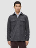 Ein Mann trägt ein doppellagiges Woll-Overshirt in der Farbe Regular Dark Grey über einem weißen Hemd mit Kragen, das ein minimalistisches skandinavisches Design widerspiegelt.
