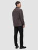 Ein Mann im Profil trägt ein doppellagiges Wollhemd in Sattelbraun über einer schwarzen Hose und schwarzen Loafern.