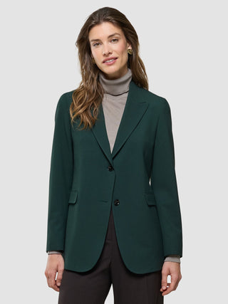 Eine Frau, die einen „Women Ease Blazer Evergreen“ über einem hellbraunen Rollkragenpullover trägt.