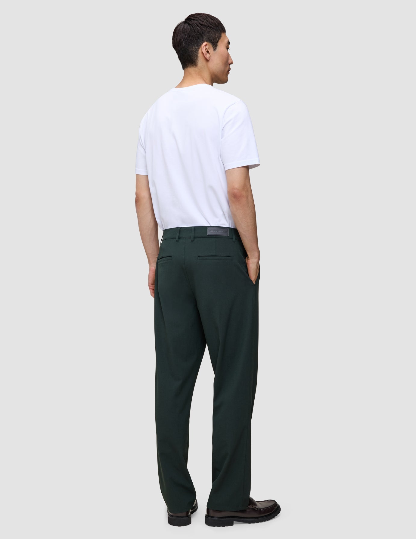 Eine Person, von hinten gesehen, die ein weißes T-Shirt und die Northern Pine Ease Pants Relaxed Fit trägt, die sich durch eine lockere Passform und 360°-Stretch auszeichnen.