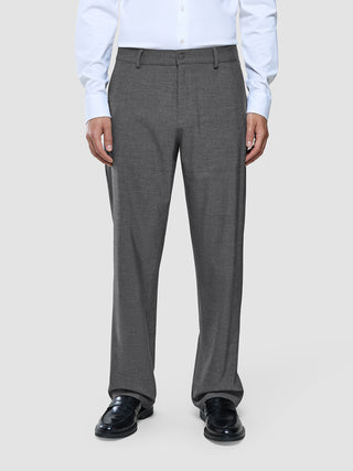 Ein Mann, der ein weißes Hemd und eine „Ease Pants Relaxed Fit“ in Dunkelgrau sowie schwarze Slipper trägt.
