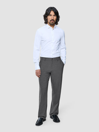 Ein Mann, der ein weißes, langärmeliges Hemd mit Knöpfen und eine „Ease Pants Relaxed Fit“ in Dunkelgrau trägt.
