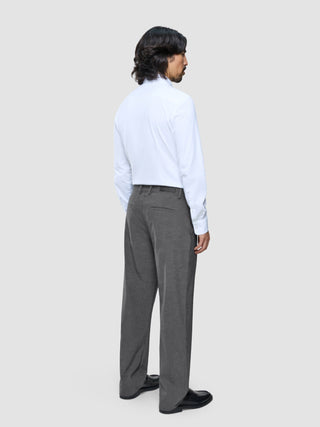 Ein Mann, von hinten gesehen, der ein weißes Hemd und eine „Ease Pants Relaxed Fit“ in Dunkelgrau trägt.
