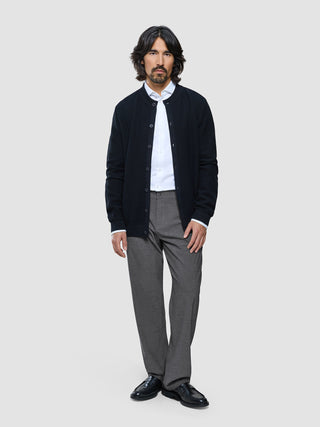 Ein Mann, der eine dunkle Strickjacke mit Knöpfen über einem weißen Hemd und eine „Ease Pants Relaxed Fit“ in Dunkelgrau trägt.