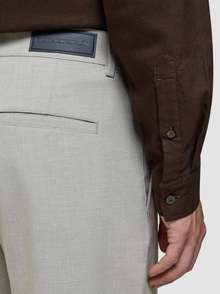 Eine Person, die ein dunkelbraunes Hemd mit Knöpfen und eine „Ease Pants Relaxed Fit Sahara“ mit einem „Shaping New Tomorrow“-Markenlabel am Bund trägt, die über 360°-Stretch verfügt.
