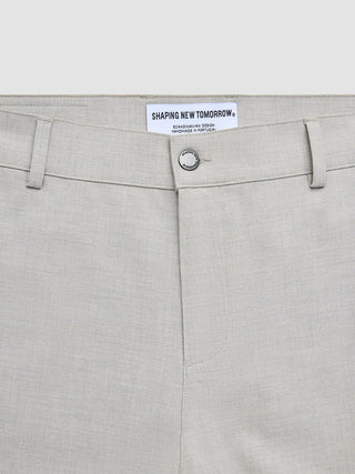 Nahaufnahme der beigen „Ease Pants Relaxed Fit Sahara“ mit einem Knopf der Marke „Shaping New Tomorrow“ und einem Innenetikett mit Angaben zum 360°-Stretch.