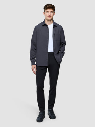 Ein Mann trägt ein dunkelgraues „Effortless“-Hemd über einem weißen T-Shirt, dazu eine schwarze Hose und schwarze Sneaker.