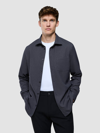 Ein Mann, der ein dunkelgraues „Effortless“-Hemd über einem weißen T-Shirt und einer schwarzen Hose trägt.