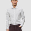 Ein Mann trägt ein hellgrau gestreiftes Elevated Shirt Regular, das er in eine dunkle Hose gesteckt hat.