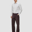 Ein Mann, der ein hellgrau gestreiftes Elevated Shirt Regular, eine dunkelbraune Hose und dunkle Slipper trägt.