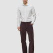 Ein Mann, der ein Elevated Shirt Regular in hellgrau gestreift aus Pima-Baumwolle trägt, dazu eine dunkle Hose und dunkle Slipper.