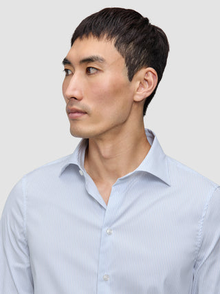 Ein Mann, der ein Elevated Shirt Slim Classic Blue Striped trägt, ein schmal geschnittenes, hellblau-weiß vertikal gestreiftes Hemd aus Pima-Baumwolle.