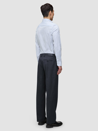 Eine Person, von hinten gesehen, die ein hellblaues, feinn gestreiftes Elevated Shirt Slim Classic Blue Striped-Hemd mit Knopfleiste trägt, das in eine dunkelgraue Hose gesteckt ist, sowie schwarze Loafer.