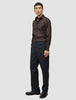 Ein Mann trägt das Elevated Shirt Slim in Dunkelbraun aus Pima-Baumwolle, dazu eine dunkle Hose und dunkle Schuhe.