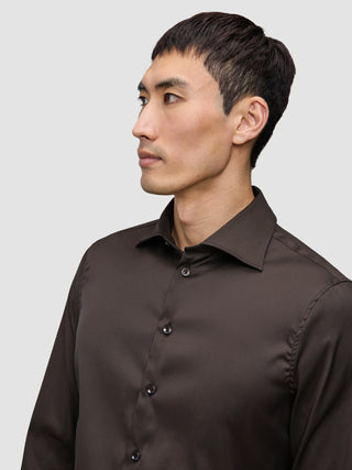 Ein Mann, der ein Elevated Shirt Slim Dark Brown trägt, ein dunkelbraunes, schmal geschnittenes Hemd mit Knöpfen.