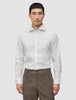 Ein Mann, der ein weißes, schmal geschnittenes Elevated-Hemd trägt, das in eine braune Hose gesteckt ist.