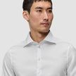 Eine Person, die ein Elevated Shirt White Slim trägt, ein knackig sitzendes, schmal geschnittenes weißes Hemd aus Pima-Baumwolle mit einem Spread-Kragen.