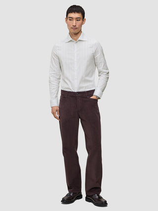 Ein Mann, der ein hellgrau gestreiftes Elevated Shirt Slim aus Pima-Baumwolle mit Knopfleiste, eine dunkle Hose und schwarze Slipper trägt.