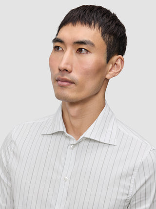Ein Mann trägt ein Elevated Shirt Slim Light Grey Striped, ein schmal geschnittenes, hellgrau gestreiftes Button-Down-Hemd aus Pima-Baumwolle mit einem Spread-Kragen.