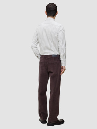 Eine Person, von hinten gesehen, die ein hellgrau gestreiftes Elevated Shirt Slim, eine dunkelbraune Hose und dunkle Slipper trägt.