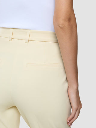 Eine Seitenansicht der „Women Essential Pants Tapered Misty Yellow“ mit hohem Bund und einer Gesäßtasche mit 360°-Stretch.