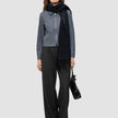 Eine Frau, die eine Essential Short Zip Jacket in Dunkelgrau-Melange, einen schwarzen Schal und eine schwarze Hose trägt und eine schwarze Handtasche bei sich hat.