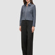 Eine Frau trägt eine Essential Short Zip Jacket in Dunkelgrau-Melange und eine schwarze Hose mit weitem Bein.