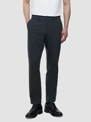 Eine Person, die ein weißes T-Shirt, eine Hose „Gen. 2.0 Pants Regular Signature“ in Dunkelgrau und schwarze Anzugschuhe trägt.