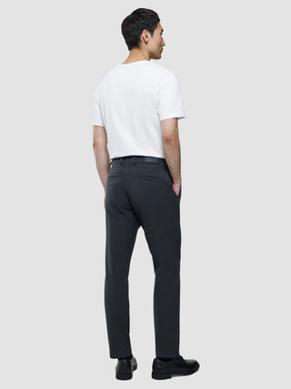 Ein Mann, von hinten gesehen, der ein weißes T-Shirt, eine „Gen. 2.0 Pants Regular Signature“ in Dunkelgrau und schwarze Schuhe trägt.