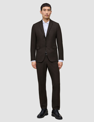 Ein Mann trägt einen dunkelbraunen Motion Blazer Regular Cognac über einem weißen Hemd mit Kragen und dazu schwarze Anzugschuhe, was eine klare, skandinavische Designästhetik widerspiegelt.