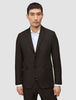 Eine Person, die einen dunkelbraunen Motion Blazer Regular Cognac über einem weißen Hemd mit Kragen trägt, das sich durch ein schlichtes, skandinavisches Design auszeichnet.