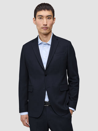 Ein Mann, der einen Motion Blazer Regular in Mitternachtsblau mit 360°-Stretch über einem hellblauen, Nadelstreifen-Hemd mit Knöpfen trägt.