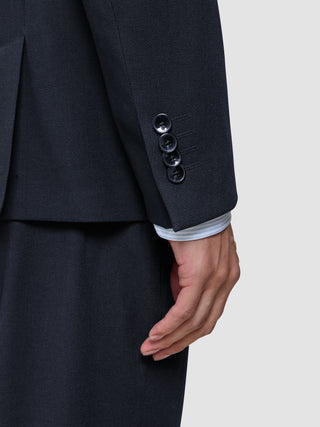 Nahaufnahme eines Ärmels des Motion Blazer Regular in Mitternachtsblau mit vier Manschettenknöpfen, unter dem der Ärmel eines weiß gestreiften Hemdes hervorblitzt – ein Beispiel für skandinavisches Design.