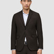Ein Mann, der einen Motion Blazer Slim Cognac trägt, einen dunkelbraunen Slim-Fit-Blazer mit 360°-Stretch, über einem weißen Hemd mit Knopfleiste.
