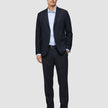 Ein Mann, der einen Motion Blazer Slim in Mitternachtsblau trägt, dazu ein hellblaues Button-Down-Hemd, eine dunkelblaue Hose, einen schwarzen Gürtel und dunkle Slipper.