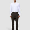 Ein Mann in einem weißen Hemd und einer Motion Suit-Hose in der Farbe Regular Cognac, kombiniert mit schwarzen Schuhen für einen eleganten Look.