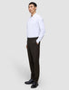 Ein Mann, im Profil zu sehen, der ein weißes, langärmeliges Hemd mit Knöpfen, eine Motion Suit-Hose in der Passform Regular in der Farbe Cognac sowie schwarze Anzugschuhe trägt und damit einen eleganten Look präsentiert.
