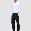 Ein Mann steht mit der Hand in der Tasche da; er trägt ein weißes Hemd und eine Motion Suit-Hose in der Passform Regular in Mitternachtsblau.