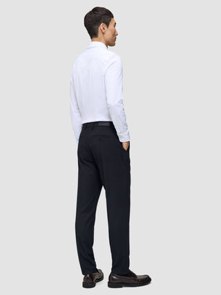 Ein Mann, von hinten gesehen, der ein weißes Hemd, Slipper und eine Motion Suit-Hose in der Passform Regular in Mitternachtsblau trägt.