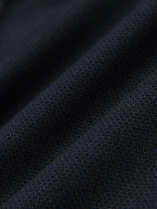 Nahaufnahme einer gefalteten Motion Suit-Hose in der Passform Regular in Mitternachtsblau mit einer sichtbaren, gewebten 360°-Stretch-Struktur.