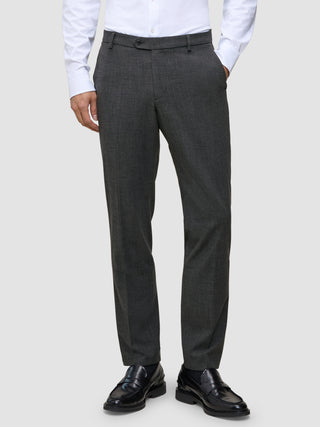 Eine Person, die eine Motion Suit Pants Regular Pepper Grey, ein weißes Hemd und schwarze Slipper trägt.