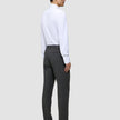 Ein Mann, von hinten gesehen, der ein weißes Hemd, eine Motion Suit-Hose in der Passform Regular in der Farbe Pepper Grey und schwarze Loafer trägt.