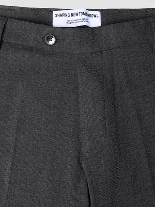 Nahaufnahme der atmungsaktiven, dunkelgrauen Motion Suit-Hose Regular Pepper Grey mit Knopfverschluss und Markenetikett am Bund.