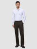 Ein Mann, der ein weißes, langärmeliges Hemd mit Knöpfen und eine Motion Suit Pants Relaxed Cognac sowie dunkle Loafer trägt.