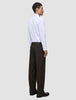 Eine Person in einem weißen Hemd und einer Motion Suit-Hose Relaxed Cognac, im Profil stehend.