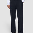 Eine Person, die eine Motion Suit-Hose Relaxed in Mitternachtsblau, ein weißes Hemd mit Knöpfen und dunkelbraune Slipper trägt.