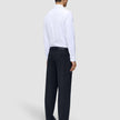 Ein Mann, von hinten gesehen, der ein weißes Hemd und eine Motion Suit-Hose im Relaxed-Schnitt in Mitternachtsblau trägt.