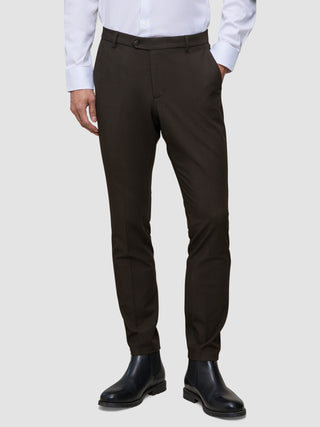 Eine Person, die ein weißes Hemd, eine schmal geschnittene, cognacfarbene Motion-Anzughose und schwarze Chelsea-Stiefel aus Leder trägt und damit einen eleganten Look präsentiert.