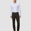 Ein Mann trägt ein weißes Hemd, eine Motion Suit-Hose in der Passform Slim in der Farbe Cognac sowie schwarze Lederstiefel und sorgt so für einen eleganten Look.