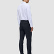 Eine Person, von hinten gesehen, die ein weißes Hemd und eine Motion Suit Pants Slim in Mitternachtsblau sowie dunkle Loafer trägt.